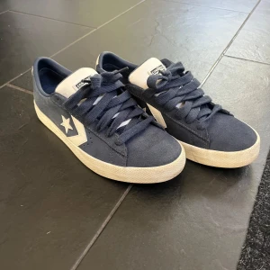 Mörkblå Converse cons sneakers i mocka - Snygga mörkblå Converse sneakers med vit sula och vita detaljer. Skorna har klassisk stjärnlogga på sidan, breda snören och ovandel i mocka. Perfekta för dig som gillar en stilren och sportig look. Säljer pga de var för små!