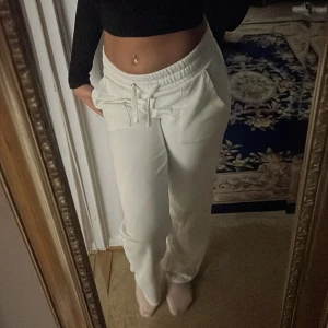 Vita mjukisbyxor med snörning - Säljer ett par vita mjukisbyxor med dragsko i midjan och fickor fram. Byxorna har relaxed fit och elastisk midja för extra komfort. Perfekta för chill dagar eller när du vill vara bekväm men ändå se fräsch ut.
