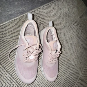 Ljusrosa Nike sneakers med mesh - Snygga ljusrosa Nike sneakers med ovandel i mesh och syntet. Skorna har rund tå, snörning och vit sula. Perfekta för dig som gillar en sportig och clean look. Diskret Nike-logga på plösen och sidan.