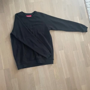 Svart sweatshirt från CCM - Svart crewneck sweatshirt från CCM med diskret logga på bröstet. Klassisk rund hals och långa ärmar, tillverkad i mjuk bomullsmix som är skön att ha på sig. Perfekt för chill dagar eller när du vill ha en enkel och stilren look.