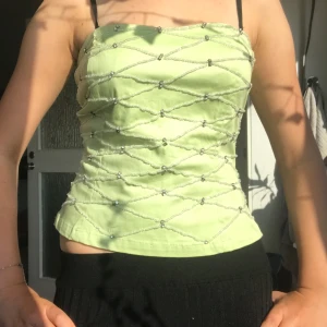 Ljusgrön pärlprydd tubtopp Lovie Paris - Superfin ljusgrön tubtopp från Lovie Paris i storlek L egentligen men jag har sytt in den till en ca en S. Toppen har ett pärlprytt rutmönster med glittriga detaljer och sidodragkedja för enkel påklädning. Materialet känns mjukt och lätt, perfekt för varma dagar. Snygg croppad passform som ger en trendig vibe. Öppen för prisförslag och skriv för frågor!