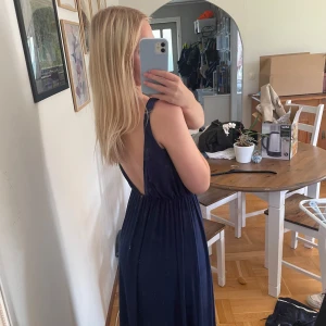 Marinblå långklänning Rare London - Säljer en marinblå långklänning från Rare London i storlek XS. Klänningen har ärmlös design, rund halsringning och har öppen rygg. Midjan är markerad med resår och tyget är lätt och faller fint. Köpt från Sellpy men den har aldrig används. Mycket bra skick!💗