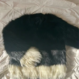 Svart och vit pälsjacka från H&M - Säljer min fluffiga pälsjacka från H&M i storlek 40. Jackan är svart upptill och övergår i vit nertill, med långhårig fuskpäls och klassisk rak passform. Perfekt till vintern