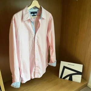 Tommy Hilfiger skjorta  - Tjenare säljer en riktigt fet Tommy Hilfiger skjorta, en ljus rosa skjorta med snygga detaljer. Skicket är väldigt bra, skulle säga 8,5/10. Storleken är L men passar mer M, killen på bilden är 180 cm. Släng iväg ett fm för frågor! 🙌🍾