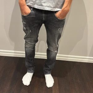 Replay svarta jeans, slim fit - Svarta Replay jeans med slitningar och snygg tvättad look. Slim fit-modell med klassiska bakfickor och detaljerade sömmar.Perfekta för dig som gillar en modern och avslappnad stil. Skriv med fler frågor.
