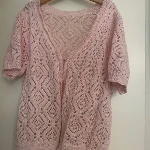 Ljusrosa stickad kofta med mönster - Supersöt ljusrosa stickad kofta med kort ärm och öppet hålmönster. Koftan är croppad och har en mjuk känsla, perfekt att slänga över ett linne. Passar till både jeans och kjol för en fin outfit!! Storlek S. Varan säljs på flera plattformar💕