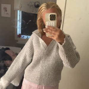 Ljusgrå stickad tröja Gina Tricot - Supermysig ljusgrå stickad tröja från Gina Tricot med bred krage och v-ringad hals. Tröjan har ribbad struktur och långa ärmar, perfekt för chill dagar. Snygg att styla med jeans eller mjukisbyxor. Aldrig använd då jag inte känner mig bekväm i stickat.