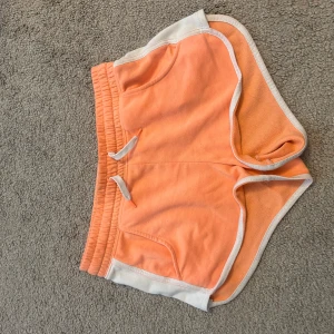 Orangea shorts  - Snygga orangea shorts från H&M med vit kant och snörning i midjan. Modellen är loose fit med elastisk midja och praktiska fickor. Lite nopprig och har en fläck på baksidan. 