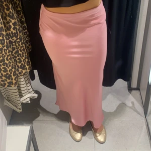Ljusrosa satinlångkjol - Säljer en superfin ljusrosa långkjol i satin med mjukt, glansigt material och enkel, rak siluett. Kjolen har en clean look utan mönster eller detaljer och sitter snyggt i midjan. Perfekt för dig som gillar stilrena vibes och vill ha en kjol som verkligen poppar. Skriv för fler bilder eller frågor!