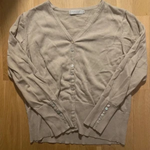 Söt kofta - Säljer en söt kofta i färgen beige, koftan sitter väldigt skönt på kroppen! Passar till båda vardag och festliga aktiviteter 🥰