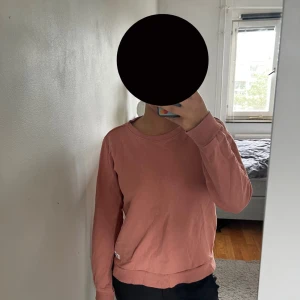 Rosa sweatshirt från 157 - Säljer en enkel och snygg rosa sweatshirt från 157. Tröjan har rund hals, långa ärmar och mjukt material på insidan. Perfekt för chill dagar och passar till både jeans och mjukisbyxor. Färgen är en soft rosa och modellen är normal i passningen.