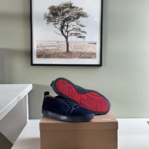 Mörkblå sneakers från Christian Louboutin - Snygga mörkblå sneakers från Christian Louboutin i mocka med klassisk röd sula och diskreta detaljer. Skorna har snörning och en stilren, låg profil som passar perfekt till streetwear eller en mer dressad look. De har slitage under då de är använda 