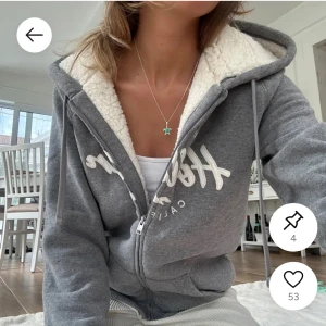 Grå hoodie Hollister med teddyfoder - Mysig grå hoodie från Hollister med vit broderad logga på bröstet och dragkedja framtill. Jag säljer då den inte kommer till användning, osäker på om den fortfarande säljs men den är väldigt populär och efterfrågad! Den passar mig som är xs o s