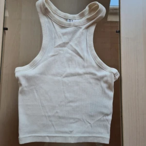 Ribbad vit linnetopp från H&M Divided - Säljer en ribbad vit linnetopp från H&M Divided i storlek XXS. Toppen har en croppad passform med breda axelband och klassisk racerback. Perfekt till jeans eller kjol för en clean och enkel look. Går att köpa 3-pack (kolla mina annonser)