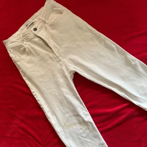 Vita jeans från Zara - Snygga vita jeans från Zara med klassisk femficksdesign och smal passform. Perfekta att styla med en oversized hoodie eller crop top. De har dock en fläck på höger ben fram, se bild. 