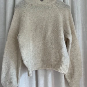 Beige stickad hoodie - Mysig beige stickad hoodie med stor huva och ribbade muddar vid ärmslut och nederkant. 