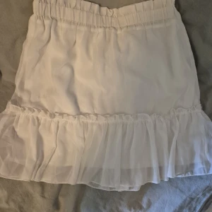 Vit kjol med volang - Supersöt vit kjol från Chelsea. Den är i storlek xs men passar även s. Använd en gång på en skolavslutning så jag säljer då den inte kommer till så stor användning.