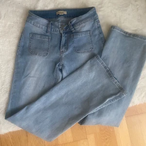 Ljusblåa jeans från Madlady - Säljer ett par ljusblå jeans från Madlady i low waist. Jeansen har stora fyrkantiga framfickor och klassiska bakfickor med knappdetalj. 36/regular