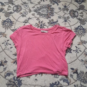 Rosa croppad topp från FB Sister - En enkel och snygg rosa croppad topp från FB Sister. T-shirten har korta ärmar, rund halsringning och är gjord i mjuk bomull. Perfekt att matcha med höga jeans eller kjol för en chill look.