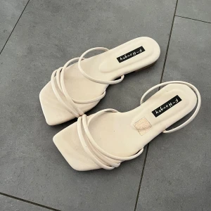 Beige sandaler från F-Honey - Köp via instabox!! Stilrena beige sandaler med fyrkantig tå och tunna remmar över foten. Platt sula och minimalistisk design, aldrig använda!