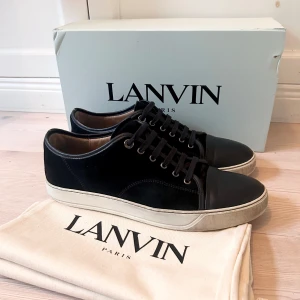 Lanvin - Stilrena marinblå sneakers från Lanvin med ovandel i mocka och tåparti i skinn i storlek UK 10 vilket motsvarar 44/45. Skorna har rund tå, marinblå snören och vit platt sula. Perfekta för dig som gillar en clean och lyxig look med premiumkänsla. 