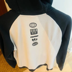 Nike Air svart och vit hoodiejacka M - Nike Air hoodiejacka i svart och vitt med dragkedja och huva. Jackan har snygga loggor på ryggen och diskret Nike Air-tryck på bröstet. Tillverkad i mjuk bomullsmix, perfekt för chill eller träning. Klassisk passform med långa ärmar och snörning i huvan.