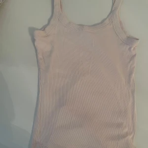 Ljusrosa ribbad linnetopp Gina Tricot - Supersöt ljusrosa ribbad linnetopp från Gina Tricot, Basically Basics-kollektionen. Toppen är ärmlös med breda axelband och har en tight passform. Perfekt att styla med jeans eller kjol för en enkel och fräsch look.