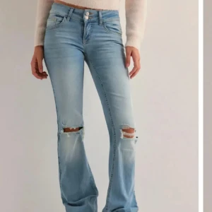 Nelly jeans - Snygga ljusblå bootcut jeans med slitna detaljer vid knäna och dubbla knappar i midjan. Baksidan har fickor med lock och knapp. Jeansen har en klassisk femficksdesign och är tillverkade i mjukt denimtyg som ger en skön passform.