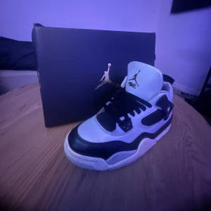 Air Jordan 4 Retro Pure Platinum/Gold - Säljer ett par Air Jordan 4 Retro i färgen Pure Platinum/Metallic Gold. Skorna har en clean vit och svart färgkombination med guldiga detaljer på tungan och hälen. Klassisk mesh och skinn, med svarta snören och ikonisk Jordan-logga. Perfekt för dig som vill sticka ut med stil.