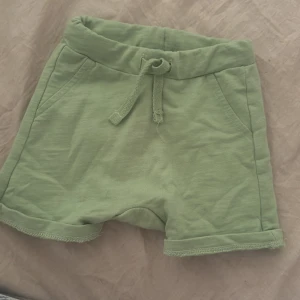 Gröna shorts med snörning från Lindex - Snygga ljusgröna shorts från Lindex med mjuk bomullskänsla. De har elastisk midja med snörning. Fina och hela. Inga fläckar eller hål