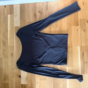 Mörkgrå långärmad topp med öppen rygg - Mörkgrå långärmad topp från ginatricot med djup öppen rygg. Aldrig använd, finns en liten sminkfläck men går säkert bort i tvätten. Prislapp kvar. 