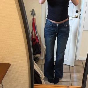 Blå bootcut jeans från weekday - Snygga blå  lite vintage jeans från weekday med klassisk bootcut-passform och låg midja. Jeansen har fyra fickor, slitningar framtill och är tillverkade i robust denim. 