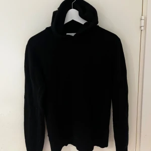 Merinoull hoodie Vailent - Svart hoodie från Vailent i mjuk merinoull, storlek XS. Tröjan har en klassisk huva och långärmade ärmar, perfekt för dig som gillar stilrena och enkla plagg. Använd endast 5 gånger. Passar dig som vill ha en varm och skön tröja med chill vibe.