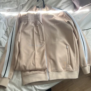 Palm angels track souit  - Säljer nu min beigea Palm angels track souit för att jag inte har någon användning av den längre. Finns fläckar på tröjan där av priset. Tar emot byten. Passar bra om man är 175-180cm