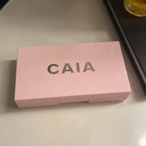 CAIA duo-palett med rouge och highlighter - Säljer en snygg CAIA duo-palett i ljusrosa plastförpackning med spegel. Innehåller ett rosa rouge och en gyllene highlighter med vågigt mönster i pudret. Perfekt för att ge ansiktet glow och färg. Paletten är kompakt och enkel att ta med i väskan. Priset kan diskuteras💞