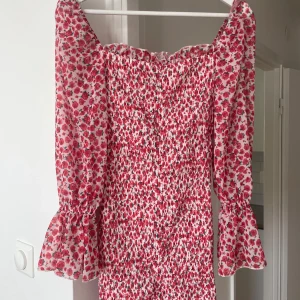 Blommig kort klänning från Parisian - Superfin kort klänning från Parisian med rött och rosa blommönster på vit botten. Off shoulder 