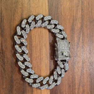 Glittrigt silverarmband med kedjelänk - Snyggt armband i silverfärg med breda kedjelänkar täckta av glittrande stenar. Låset är också dekorerat med stenar för extra bling. Perfekt för dig som vill sticka ut och ge din outfit en lyxig touch. Finns extra länkar✅️