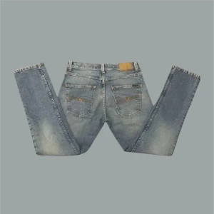 NUDIE GRIM TIM - Säljer dessa fina Nudie jeans i den populära modellen Grim Tim! Byxorna är i toppskick men har en YTTERS liten prick vid knät. Helt osynlig när man har på sig dem (se sista bilden). Dessa är även i en sample färg som heter "summer storms" och vad jag vet går inte att få tag på längre. Jeansen är lite mera ljusblå i verkligheten än på bilderna och mått finns ifall man vill ha. Tveka inte att höra av dig vid frågor!