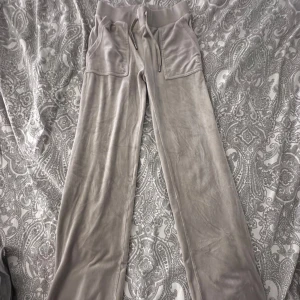 Beige byxor Juicy Couture XS - Säljer ett par beige byxor från Juicy Couture i storlek XS. Byxorna har breda ben, stora fickor fram och bak samt snörning i midjan. Perfekta för en chill och trendig look, mjuka och sköna med loose passform.
