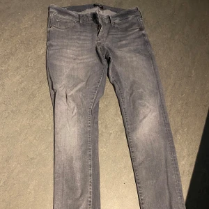 Slim Glenn grå jeans storlek 34/34 - Snygga grå jeans från Slim Glenn i slim fit-modell. Jeansen har klassisk femficksdesign, dragkedja och knapp i midjan. Materialet är mjukt denim och färgen är en tvättad grå ton som passar till