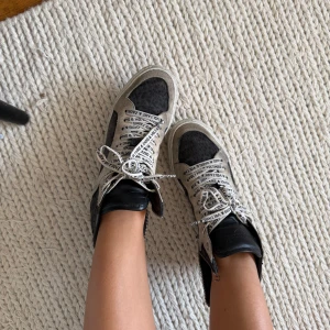 Svarta och beige sneakers Zadig & Voltaire - Säljer ett par coola high-top sneakers från Zadig & Voltaire i svart och beige mocka med leopardmönster. Skorna har vita snören med logotyptryck, rund tå och platt sula. Svarta detaljer i skinn vid ankeln och dragkedja på sidan för extra edge.