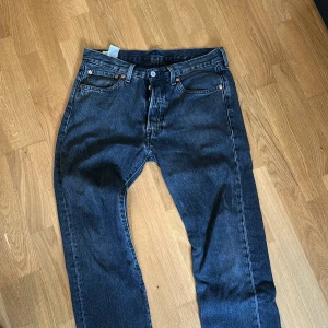 Levi's 501 mörk gråa jeans  - Säljer ett par klassiska Levi's 501 jeans i mörk grå färg i väldigt fint skick. Perfekt för dig som gillar tidlös stil och vill ha ett par jeans med autentisk känsla. 