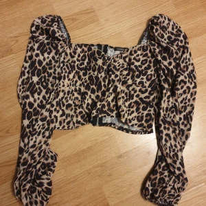 Leopardmönstrad croppad blus Boohoo - Säljer en croppad blus från Boohoo med leopardmönster i beige och svart. Toppen har puffiga långärmar och en snygg dragkedja bak. Materialet är lätt och luftigt. Jättefin! Men inte riktigt min stil. Skulle säga att den är liten i storlek.