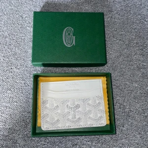 Vit designer plånbok med mönster - Säljer en stilren vit plånbok med det ikoniska mönstret och diskret logga framtill. Plånboken har flera kortfack och är tillverkad i exklusivt skinn. Perfekt för dig som vill ha något lyxigt och unikt i fickan. Boxen medföljer ej!