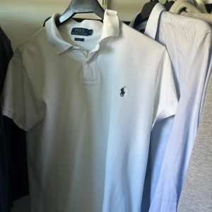  Ralph Lauren piké - Vit pikétröja från Polo Ralph Lauren med klassisk krage och två knappar vid halsen. Perfekta tröjan för en clean och stilren look. M fits S