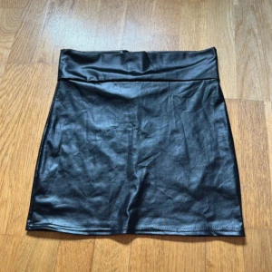 Svart kort kjol i skinnimitation - Säljer nu denna kjol då den aldrig kommit till användning!🩶 Vet tyvärr inte vart den kommer ifrån!🩶