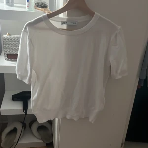 Vit stickad tröja från Zara - Säljer en vit stickad tröja från Zara i storlek M. Tröjan har rund hals, korta ärmar och ribbade muddar vid ärmslut och nederkant. Enkel och clean design som funkar till många olika stilar. Perfekt för dig som gillar minimalistiskt och fräscht. Använd en gång