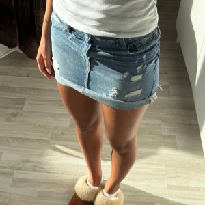 Blå jeanskjol från Zara - Snygg blå jeanskjol från Zara med slitna detaljer och rå kant nedtill. I storlek xs!