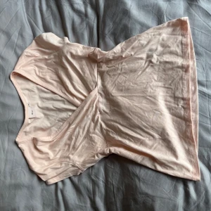 Ljusrosa omlottopp från Nelly - Supersöt ljusrosa omlottopp från Nelly med v-ringad hals och korta ärmar. Toppens mjuka bomullsmaterial gör den skön att bära och den har en feminin passform som framhäver midjan. Perfekt för dig som gillar en enkel men chic look.