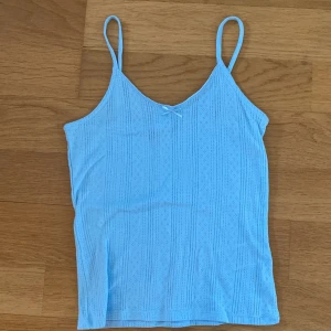 Ljusblå linnetopp från Vero Moda - Supersöt ljusblå linnetopp från Vero Moda med tunna axelband och liten rosett framtill. Perfekt för varma dagar och enkel att matcha med jeans eller kjol.